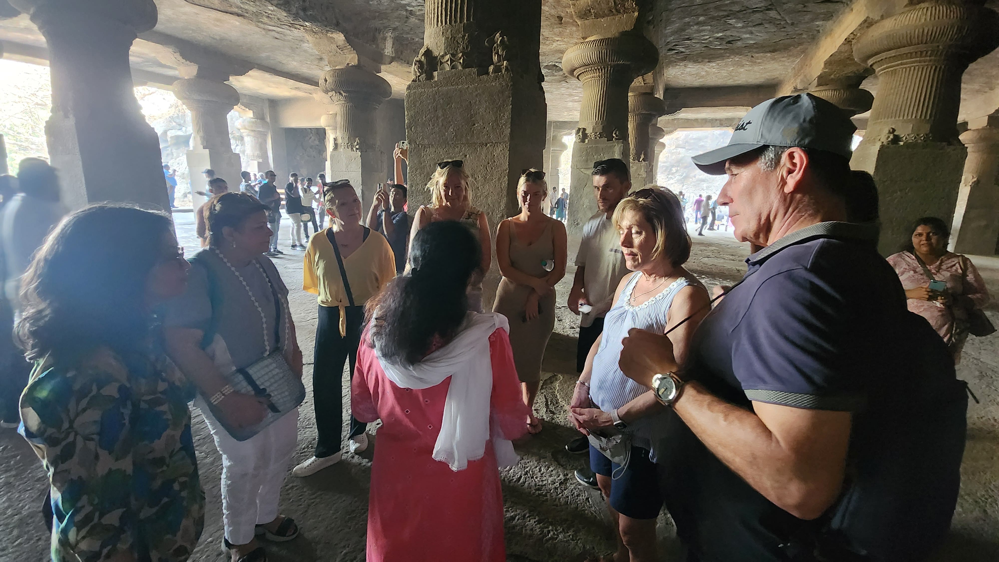 International travelers listening to a local guide inside Elephanta Caves on an immersive speedboat tour from Mumbai