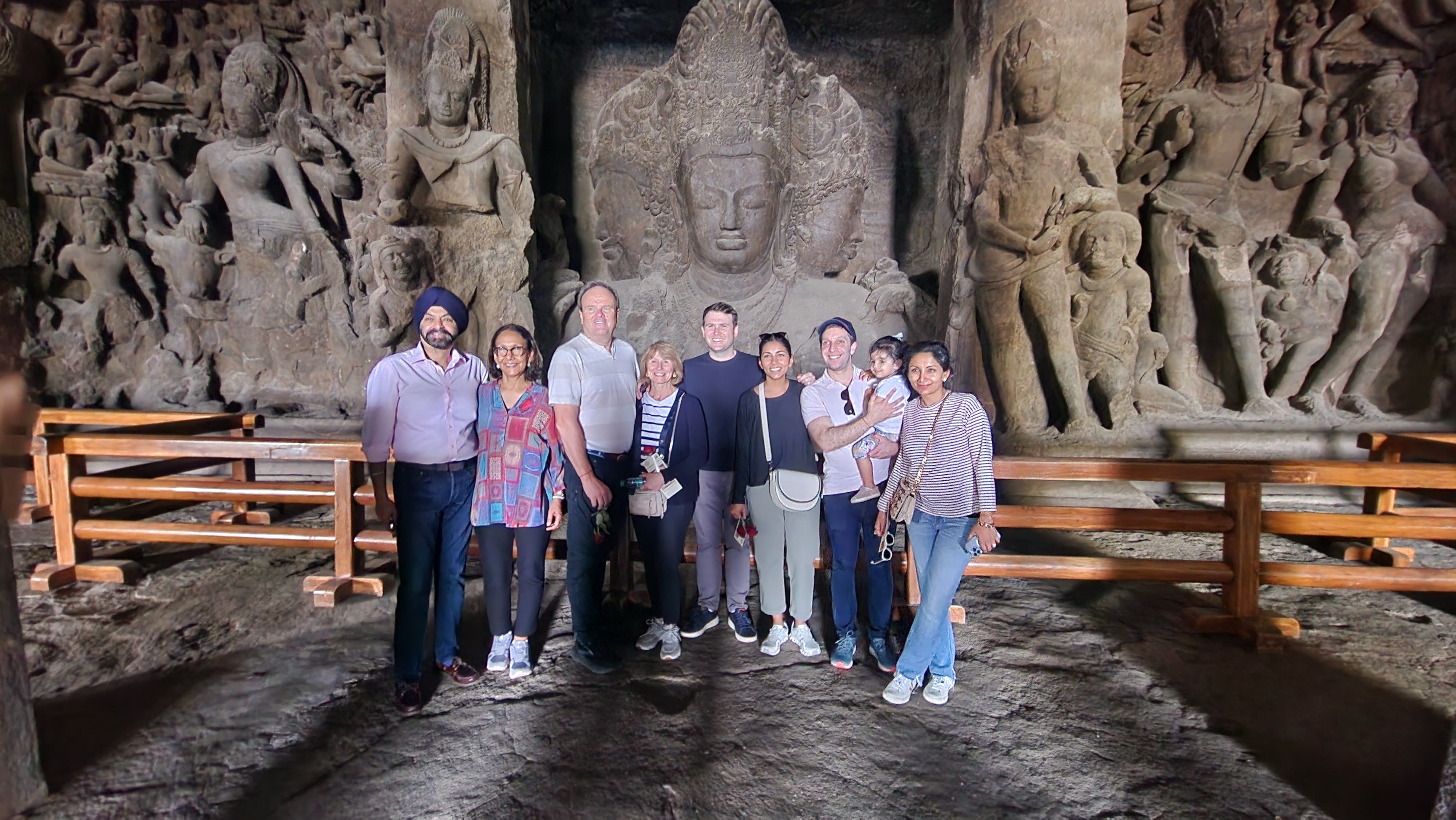 Group photo of visitors at the Trimurti Shiva sculpture inside Elephanta Caves after arriving by speedboat