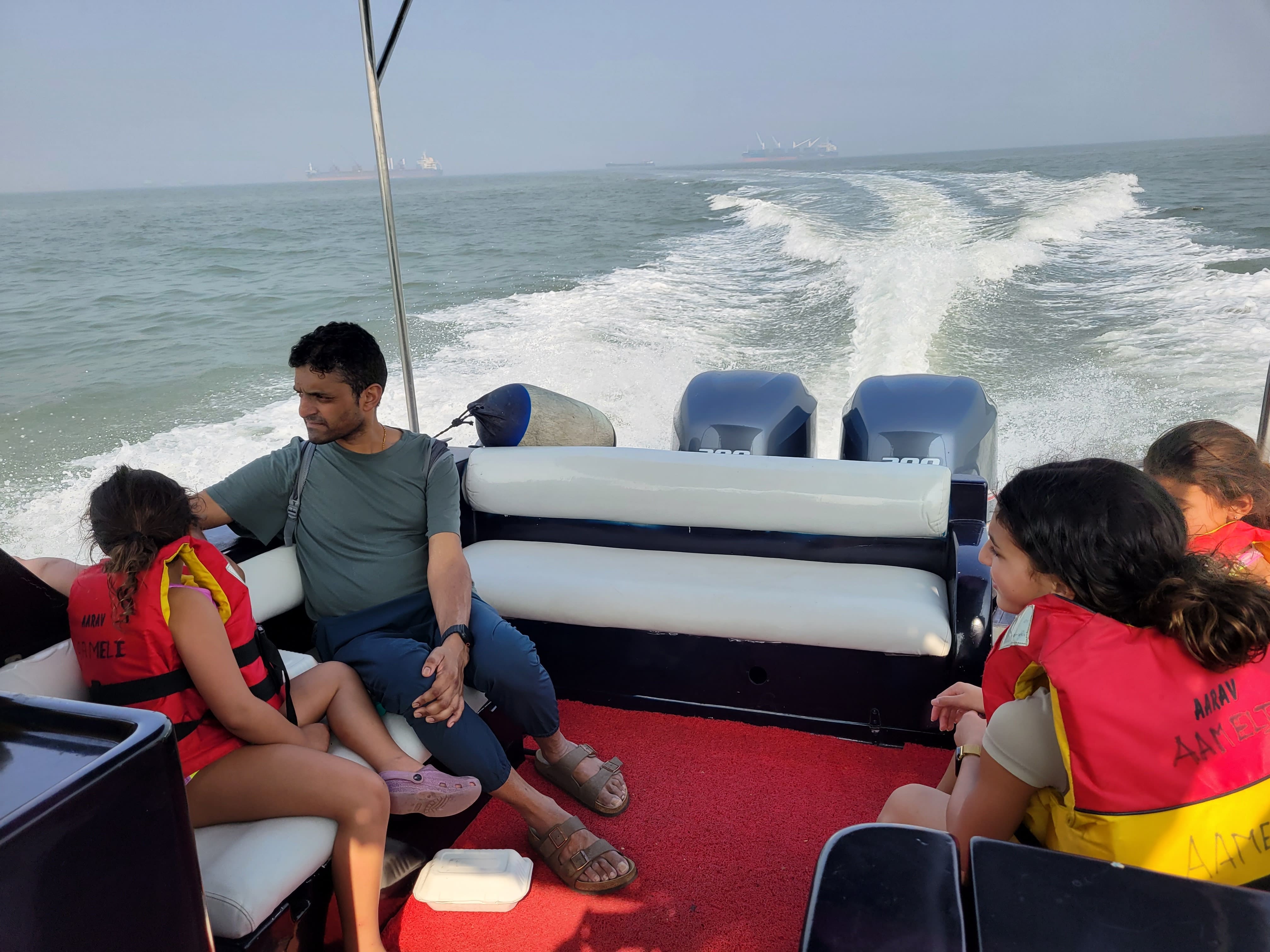 Happy tourists returning by speedboat with Mumbai skyline views after visiting Elephanta Island