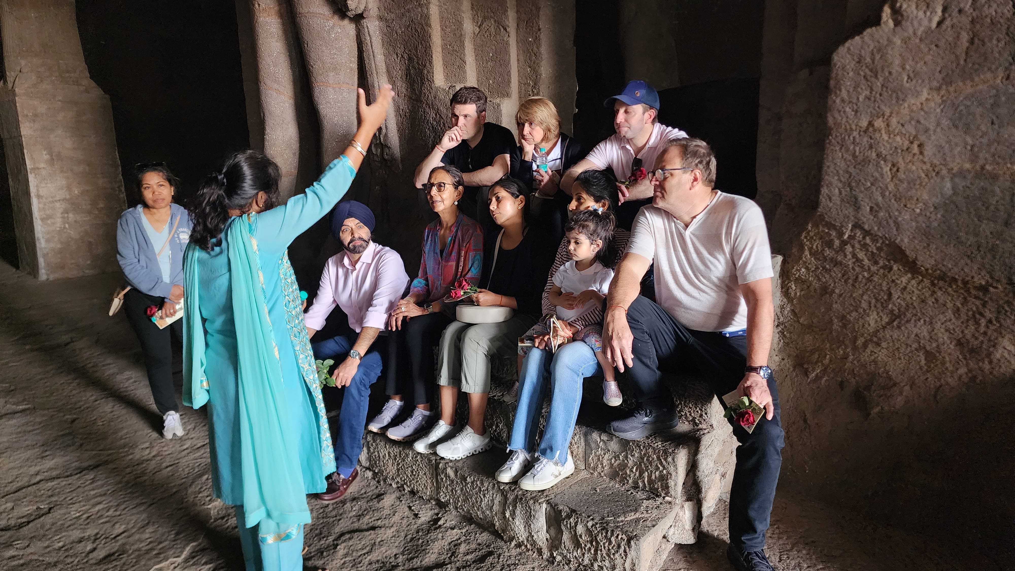 Local guide explaining Elephanta Caves history to international travelers during a guided speedboat tour from Mumbai