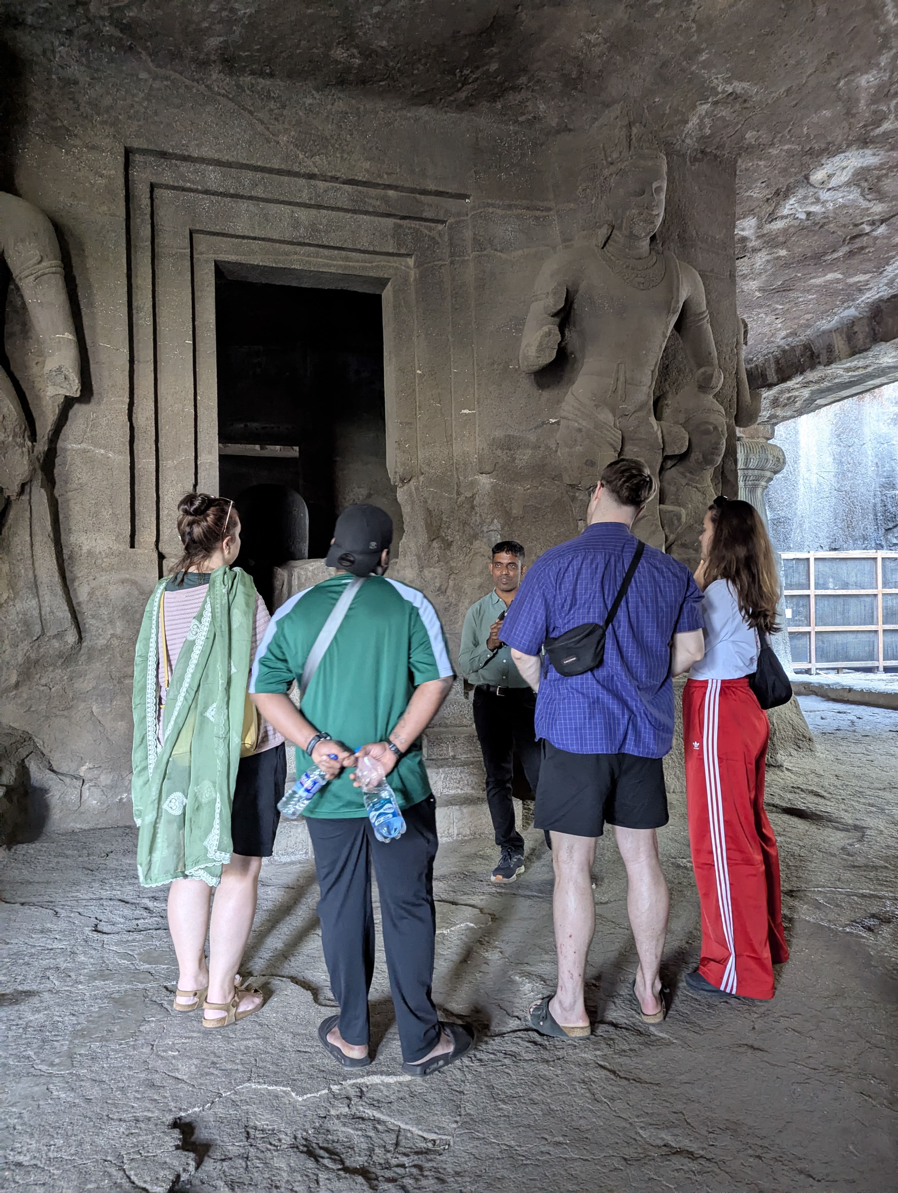Guided explanation of ancient rock-cut sculptures inside Elephanta Caves during a speedboat tour