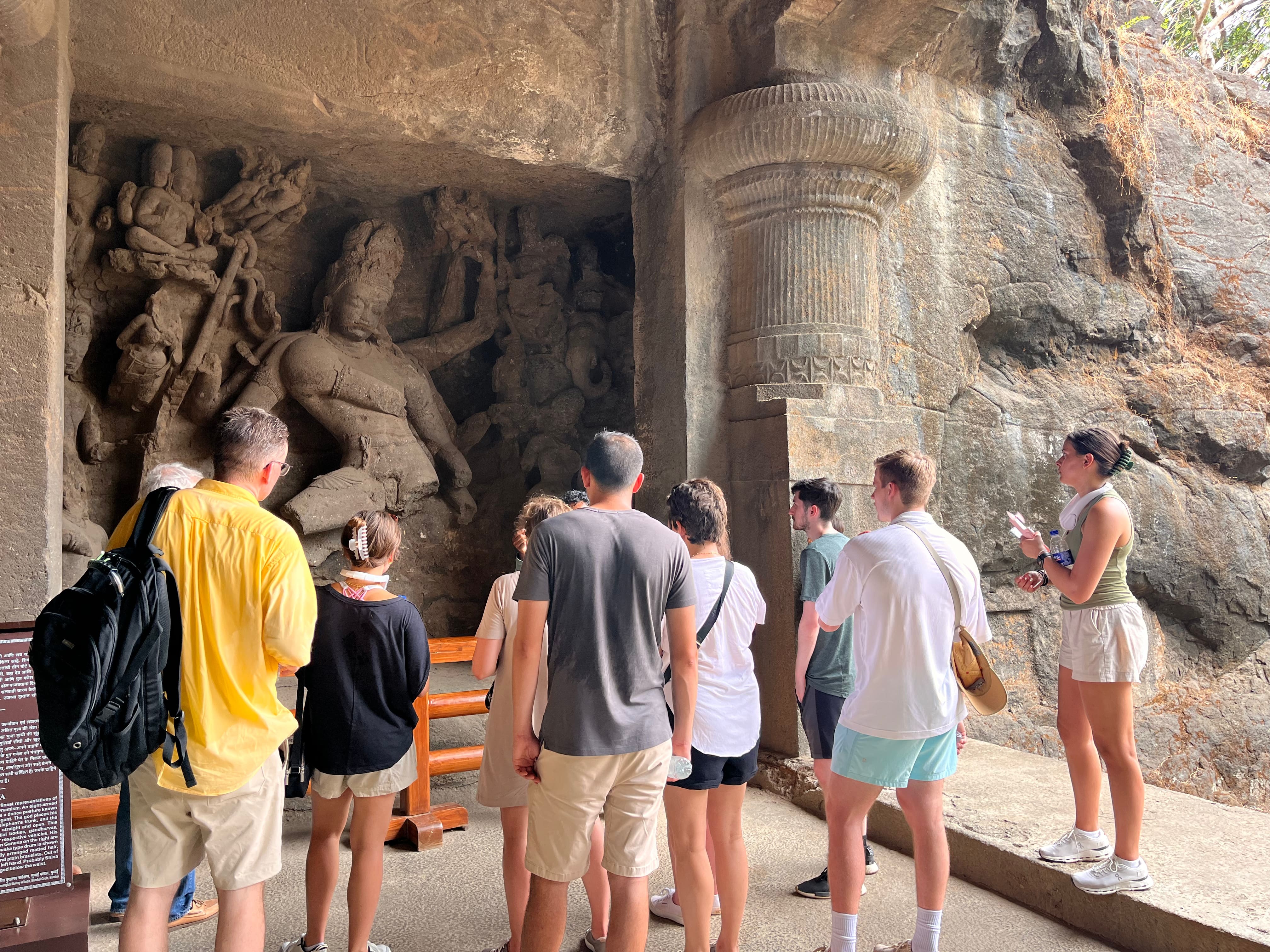 Visitors observing a monumental Shiva sculpture inside Elephanta Caves as part of a guided speedboat tour from Mumbai