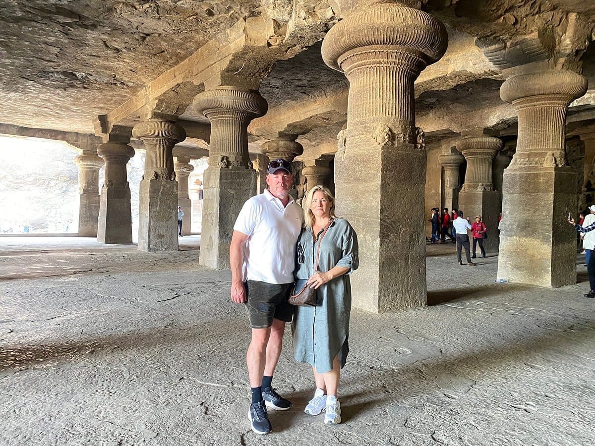 Couple standing among massive basalt pillars inside Elephanta Caves during guided exploration